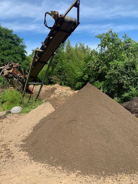 A pile of dirt is being conveyed by a conveyor belt
