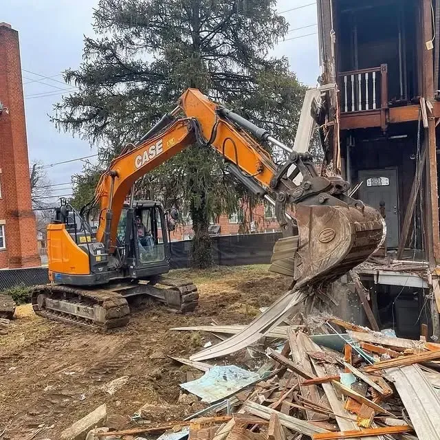 An orange case excavator is demolishing a building