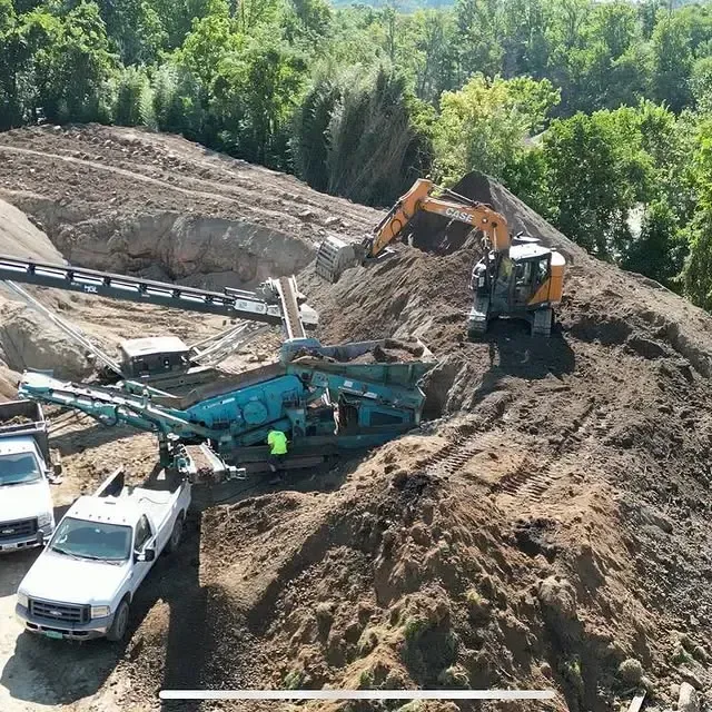 A large pile of dirt is being loaded onto a conveyor belt