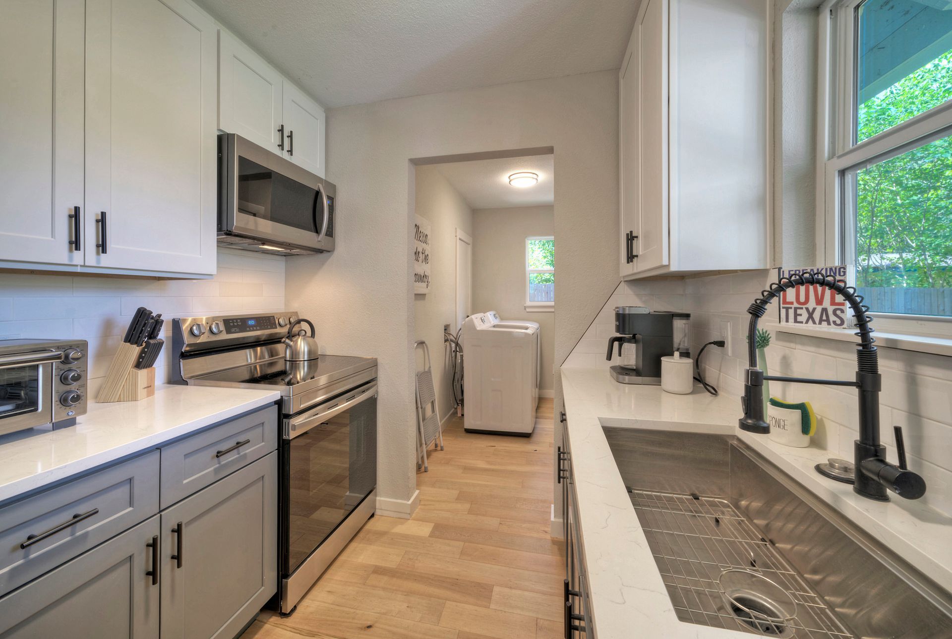 A kitchen with stainless steel appliances , white cabinets and a sink.