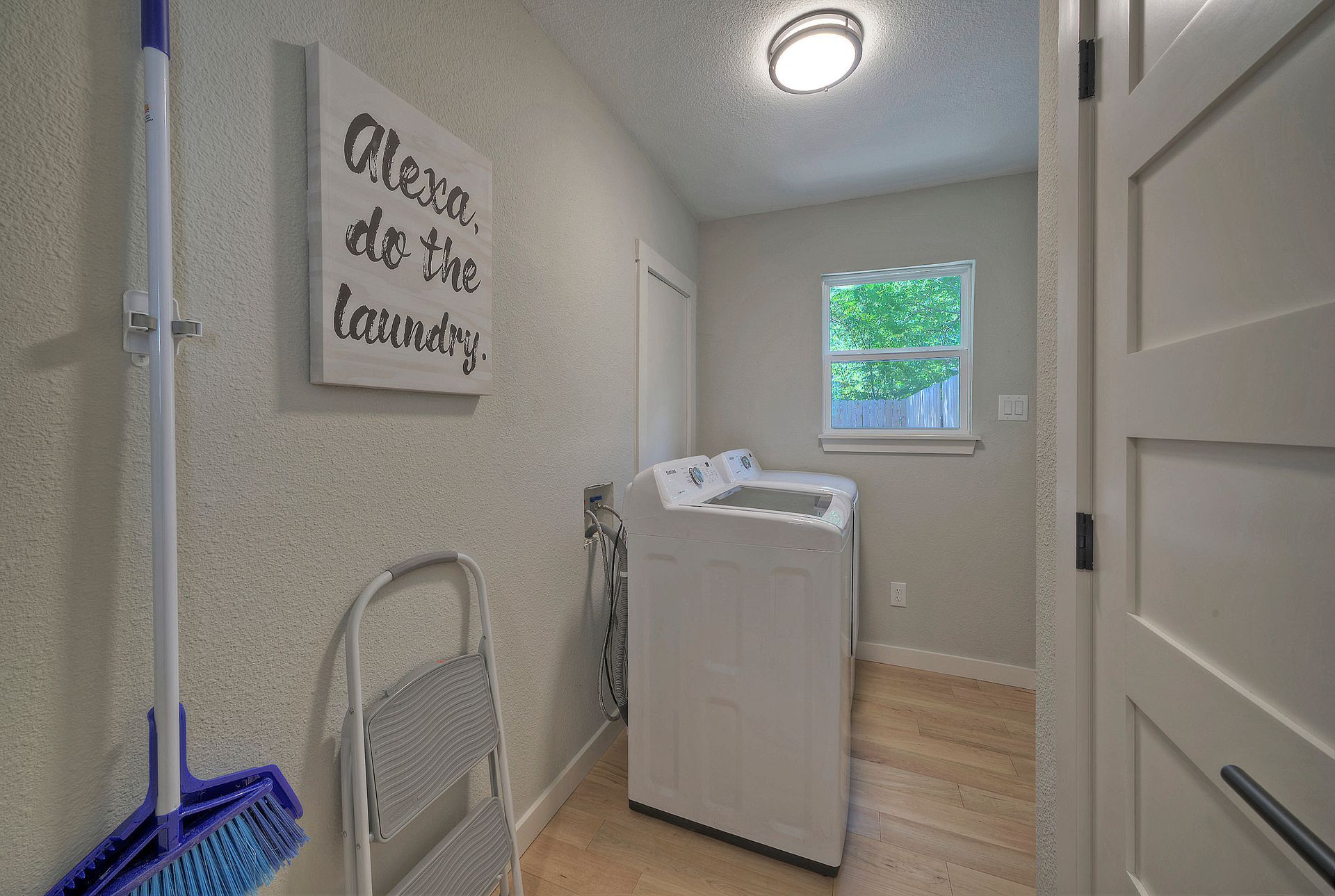A laundry room with a washer and dryer and a sign on the wall that says `` alexa do the laundry ''.