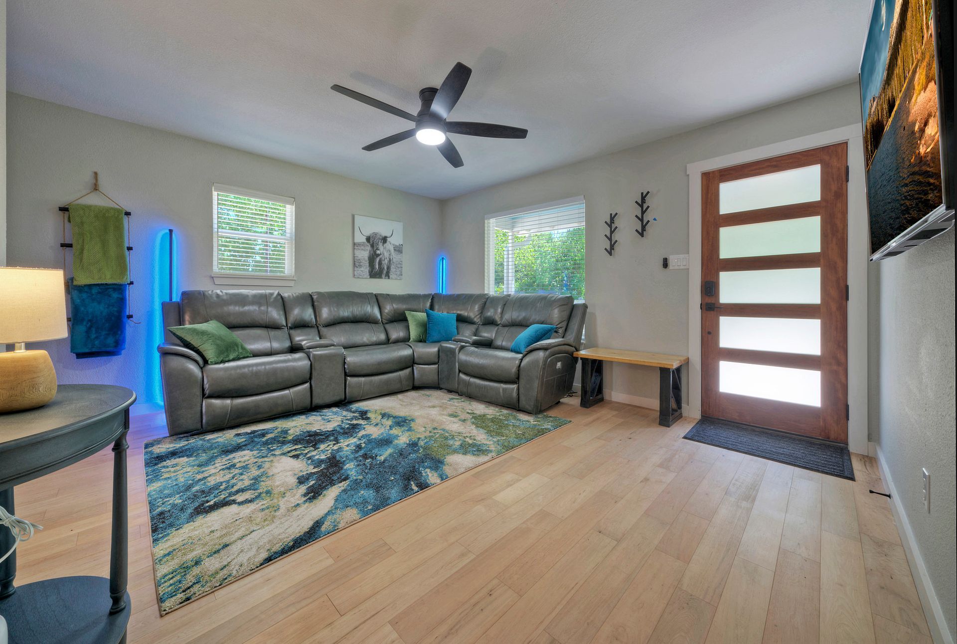 A living room with a large sectional couch and a ceiling fan.