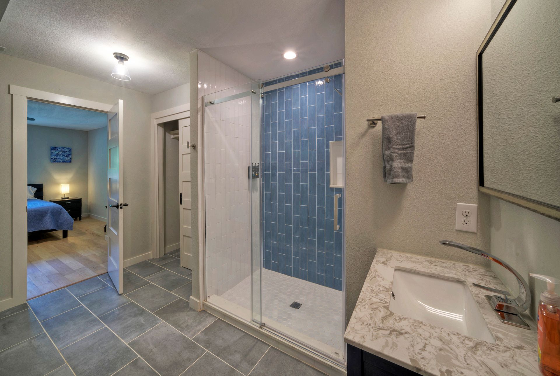 A bathroom with a walk in shower , sink and mirror.