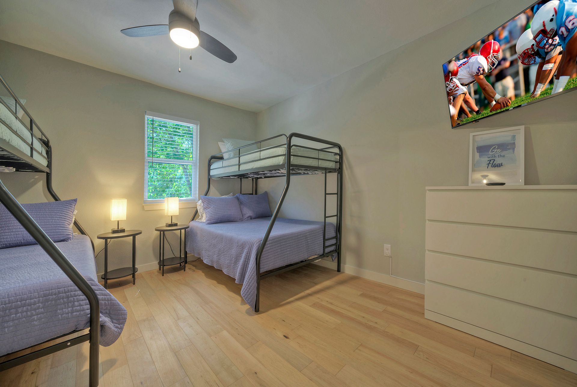 A bedroom with bunk beds and a television on the wall.
