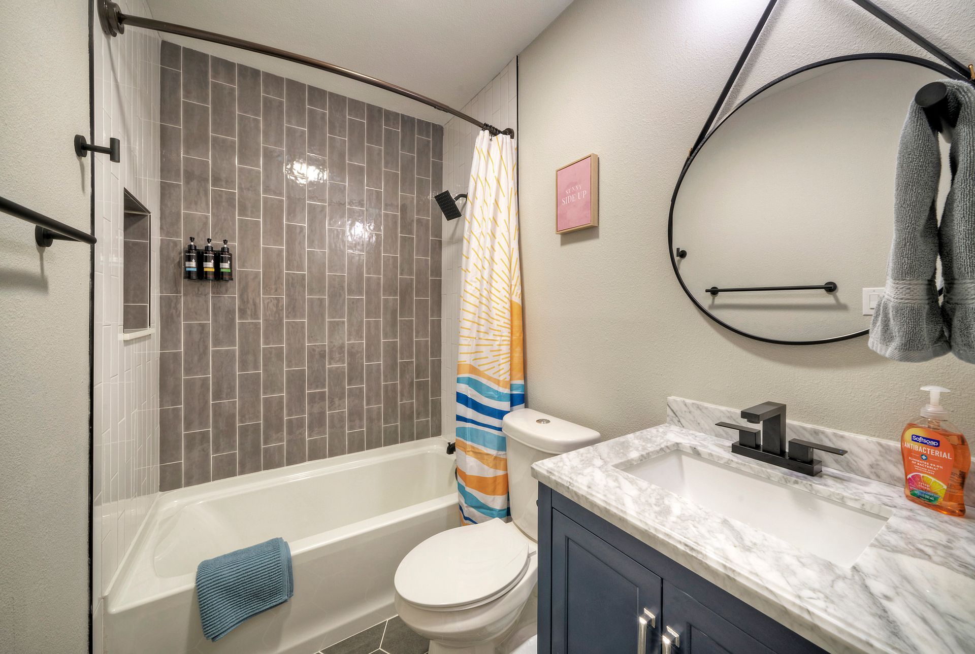 A bathroom with a toilet , sink , tub and mirror.