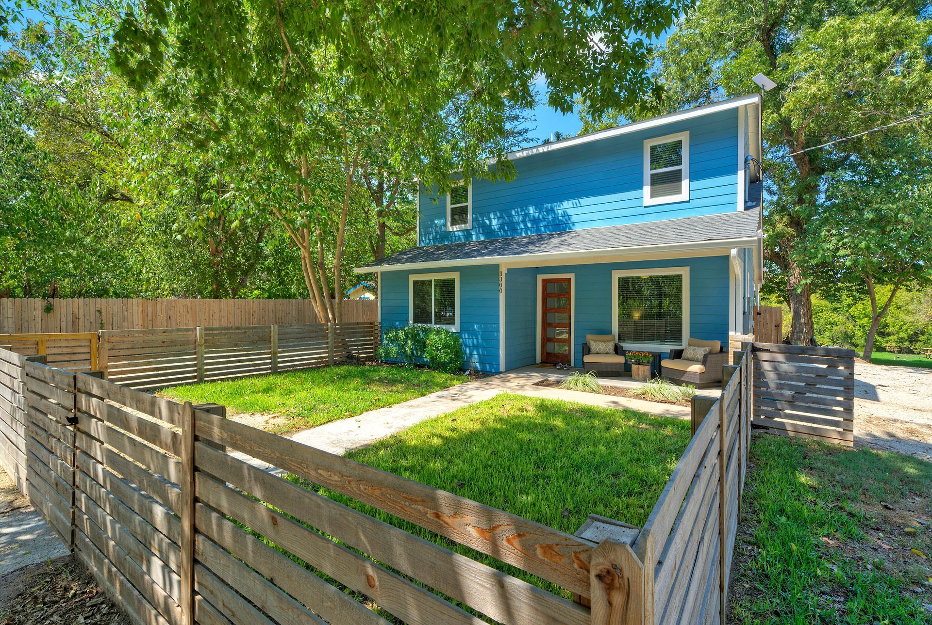 A blue short term rental house with a wooden fence in front of it.