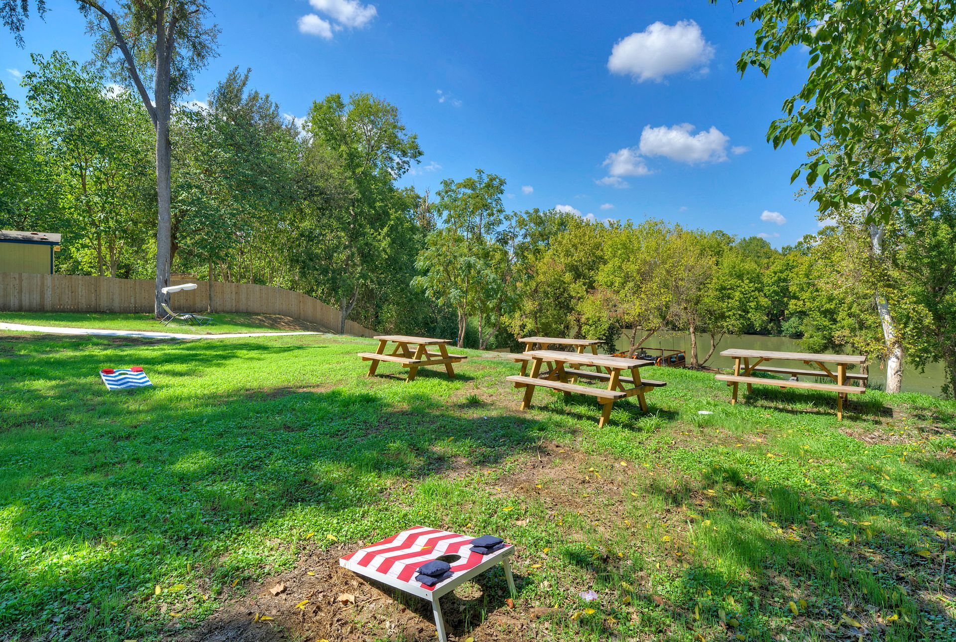 A group of picnic tables are sitting on top of a lush green field with yard games.