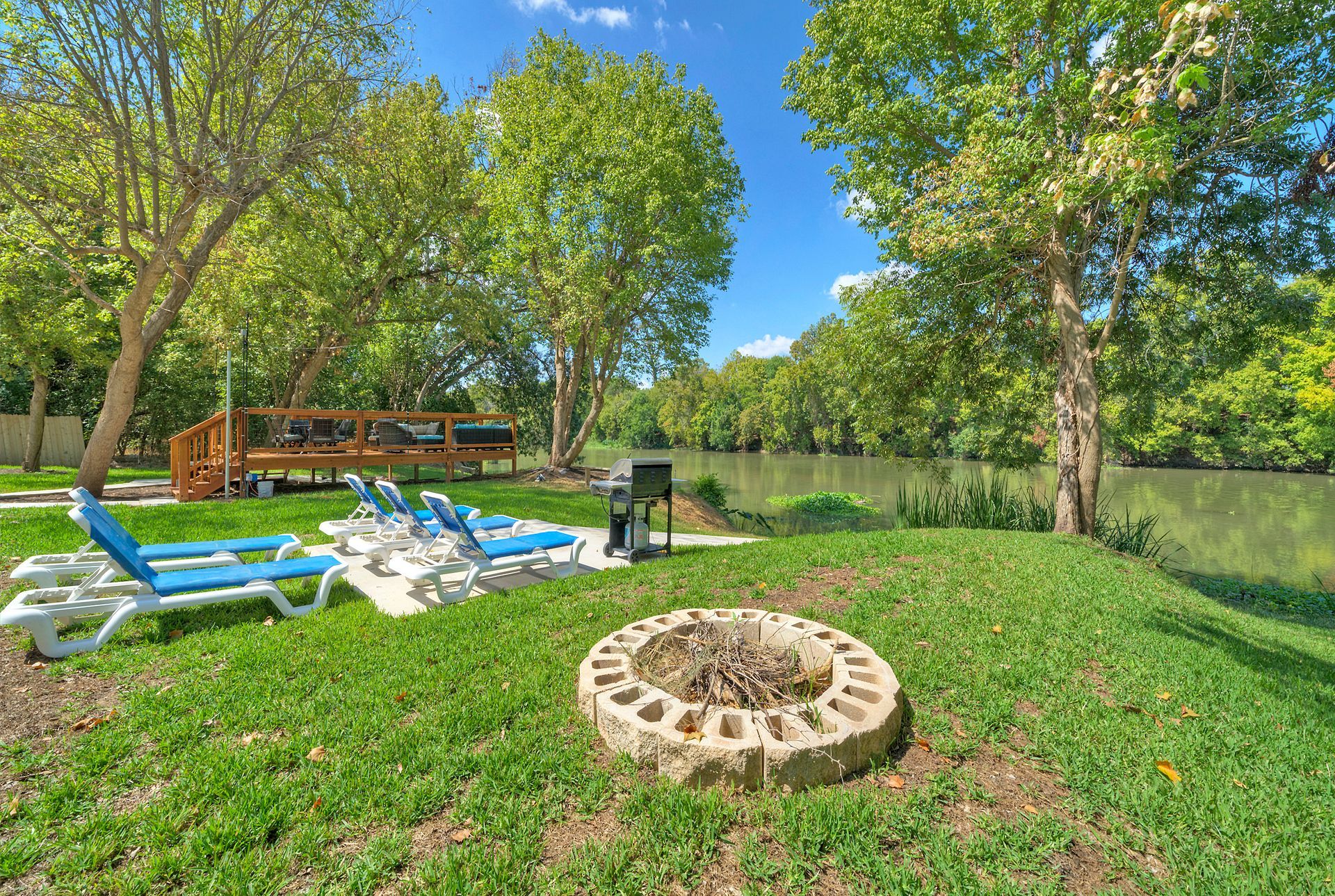 There is a fire pit in the middle of the grass next to a river.