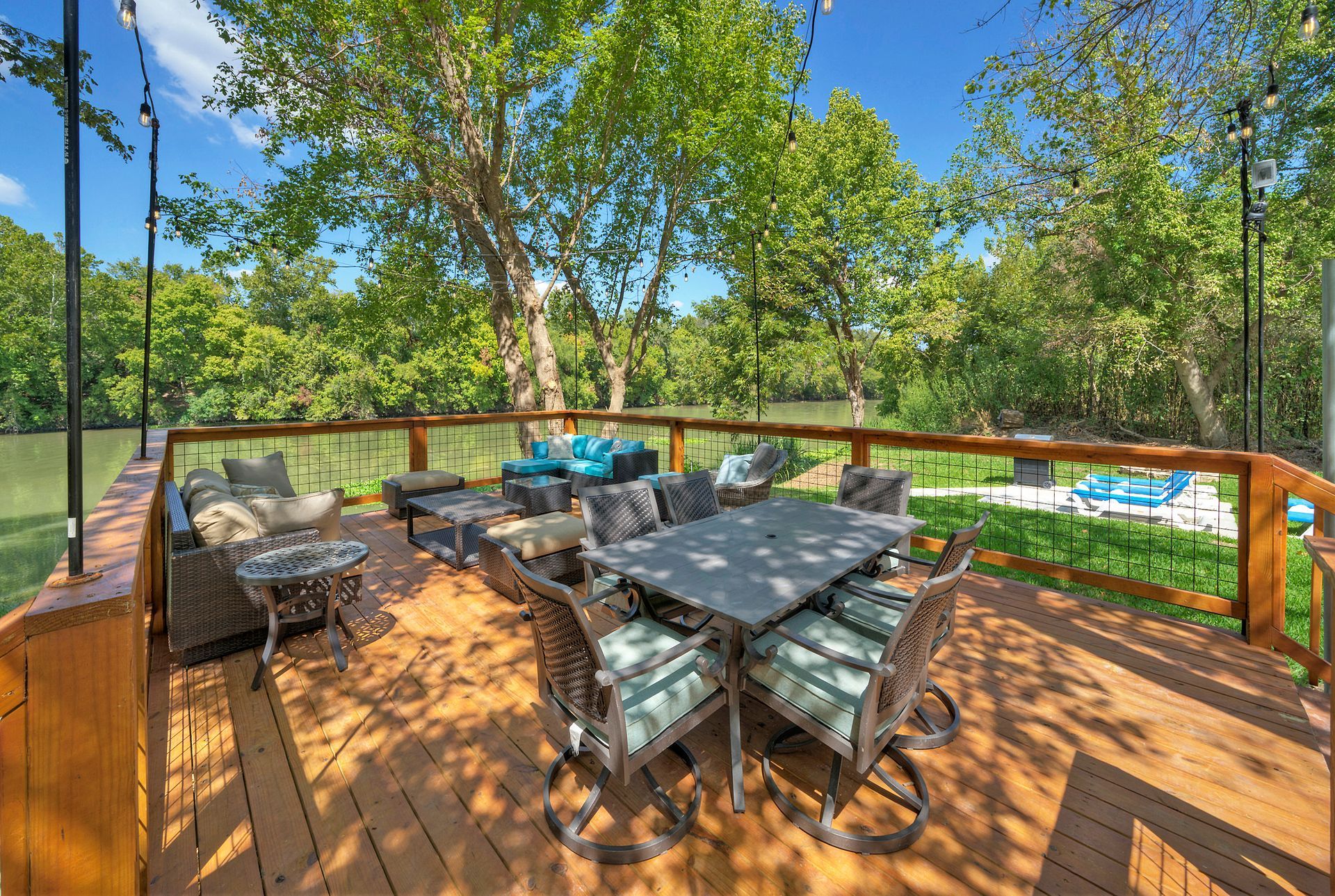 A large wooden viewing deck with a table and chairs on it in front of the Colorado River.