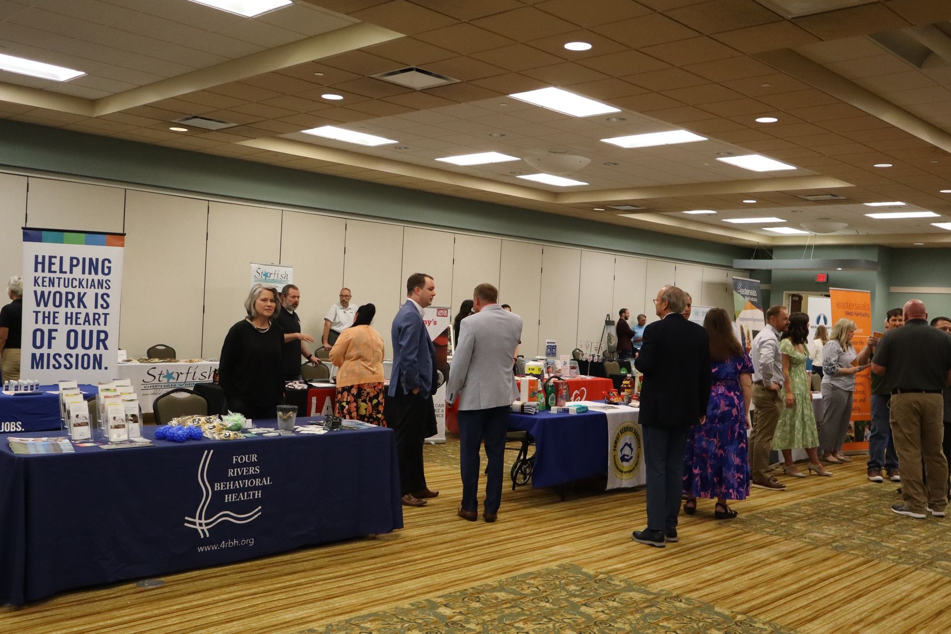 People at tables in a conference room, networking and browsing.