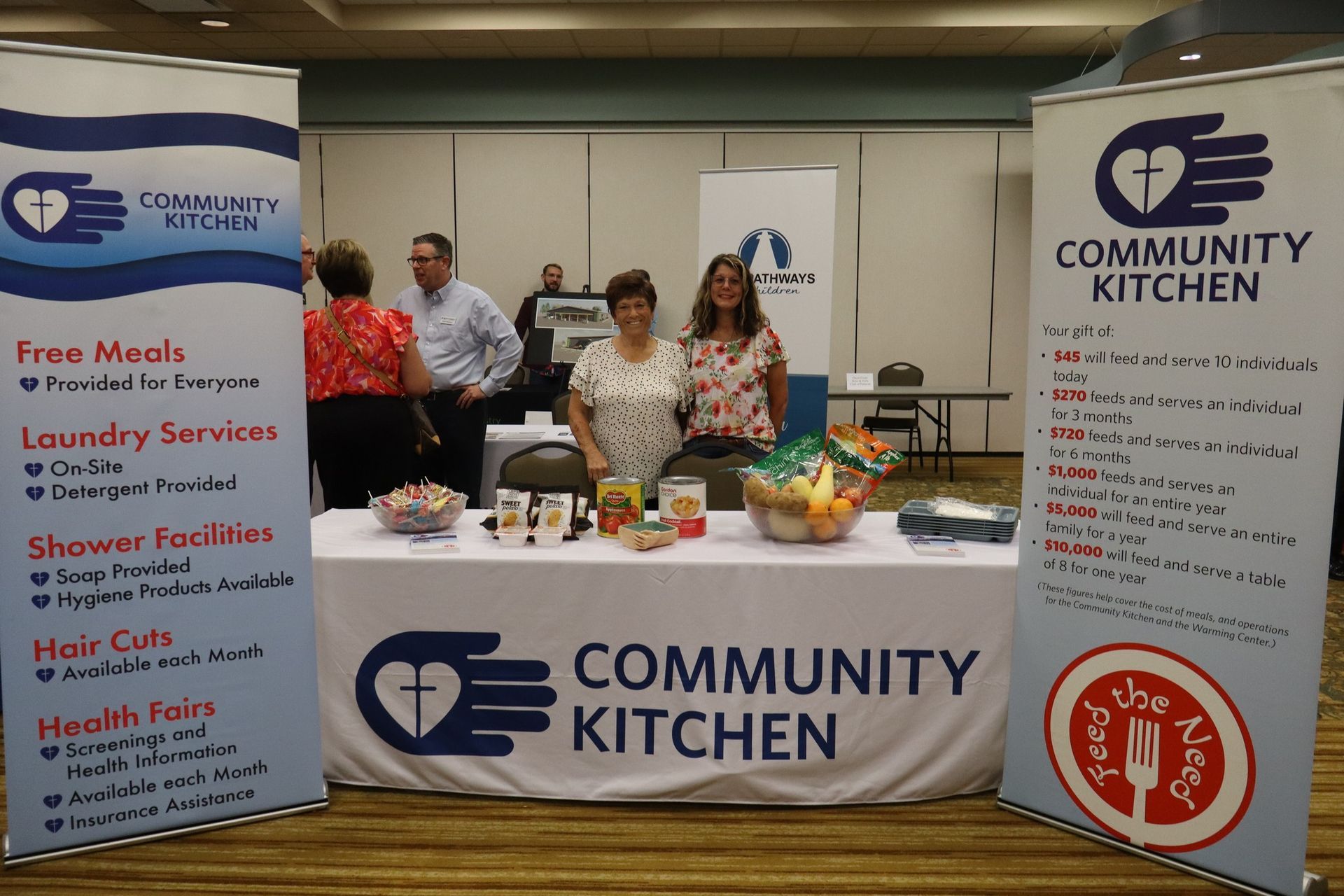 Community Kitchen booth with people, offering free meals, laundry, showers, and health services.