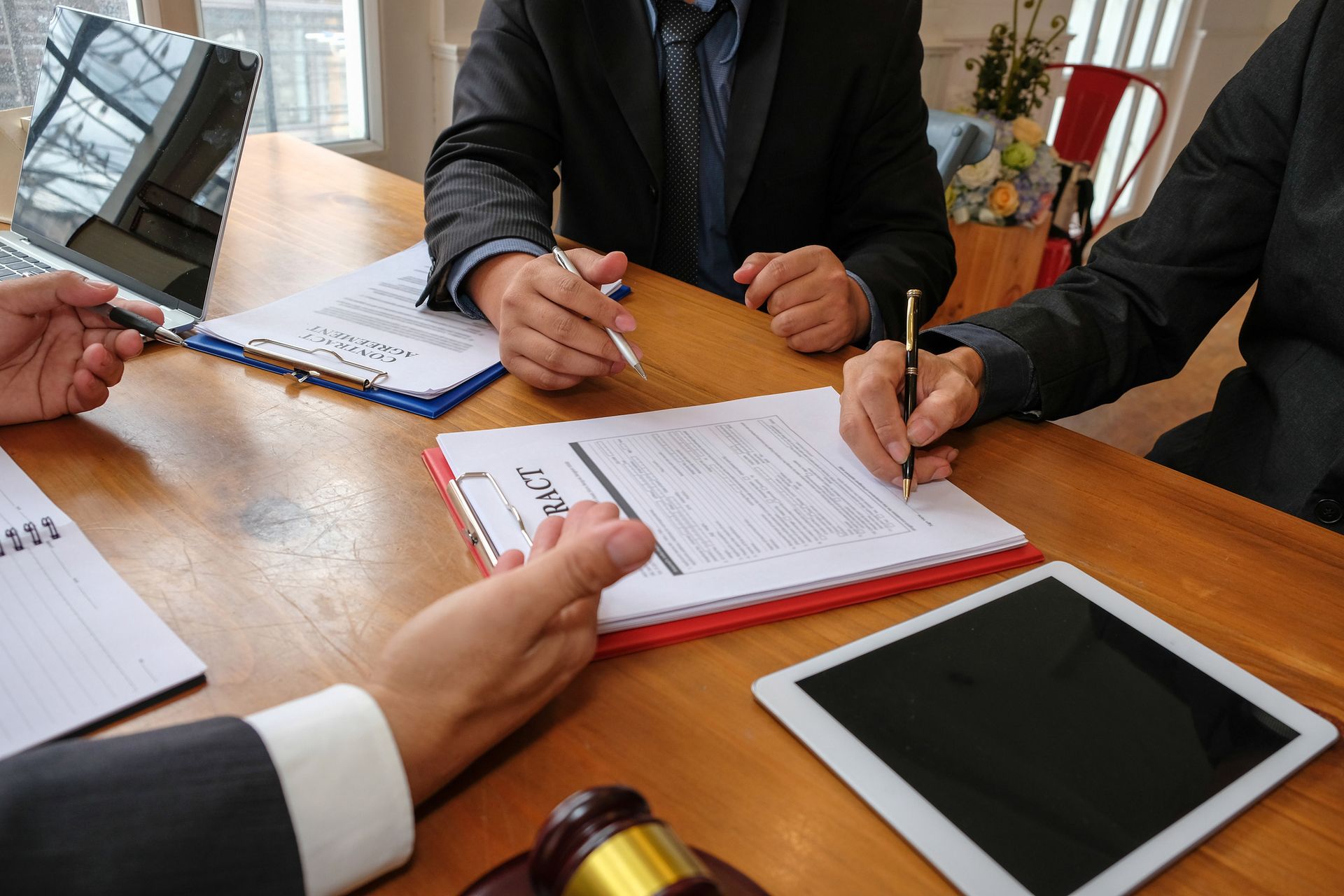 A group of people are sitting at a table with papers and a tablet.