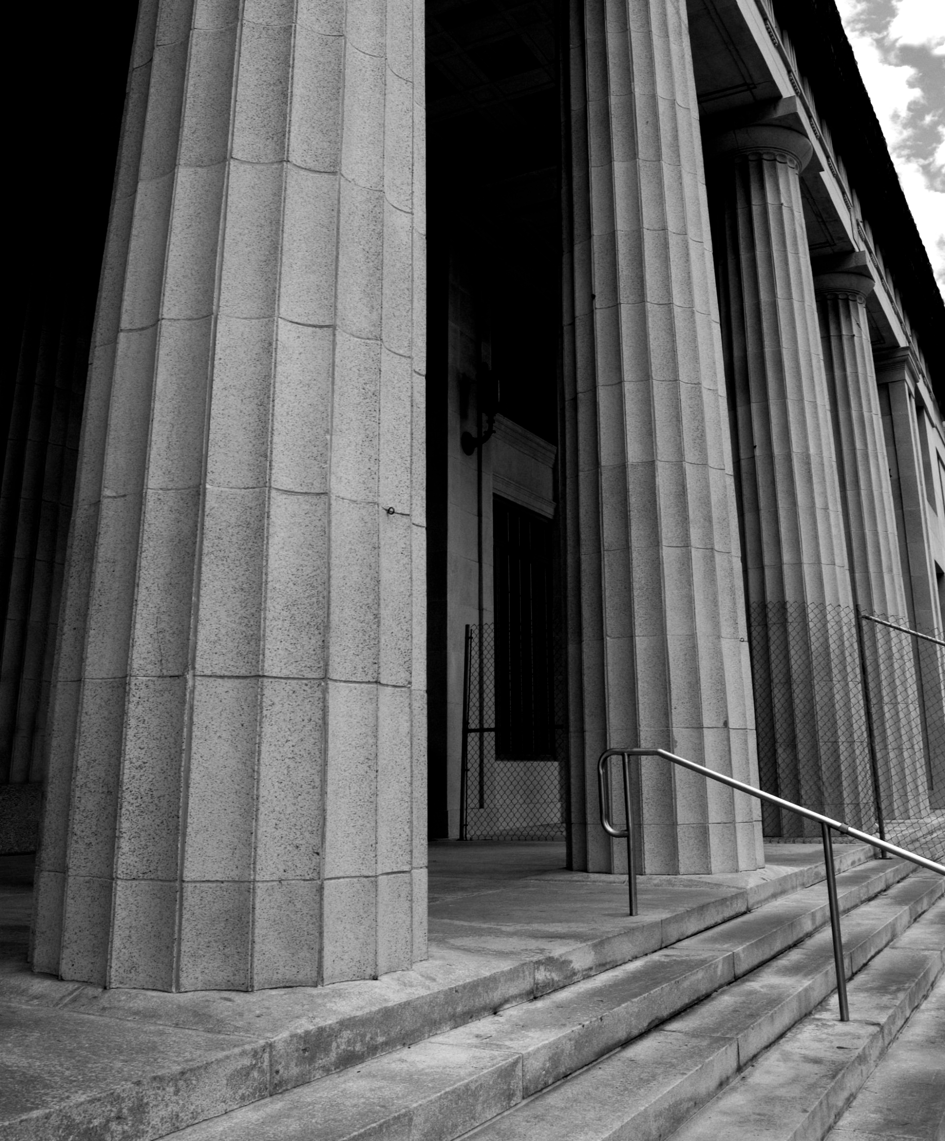 A black and white photo of a building with columns and stairs.