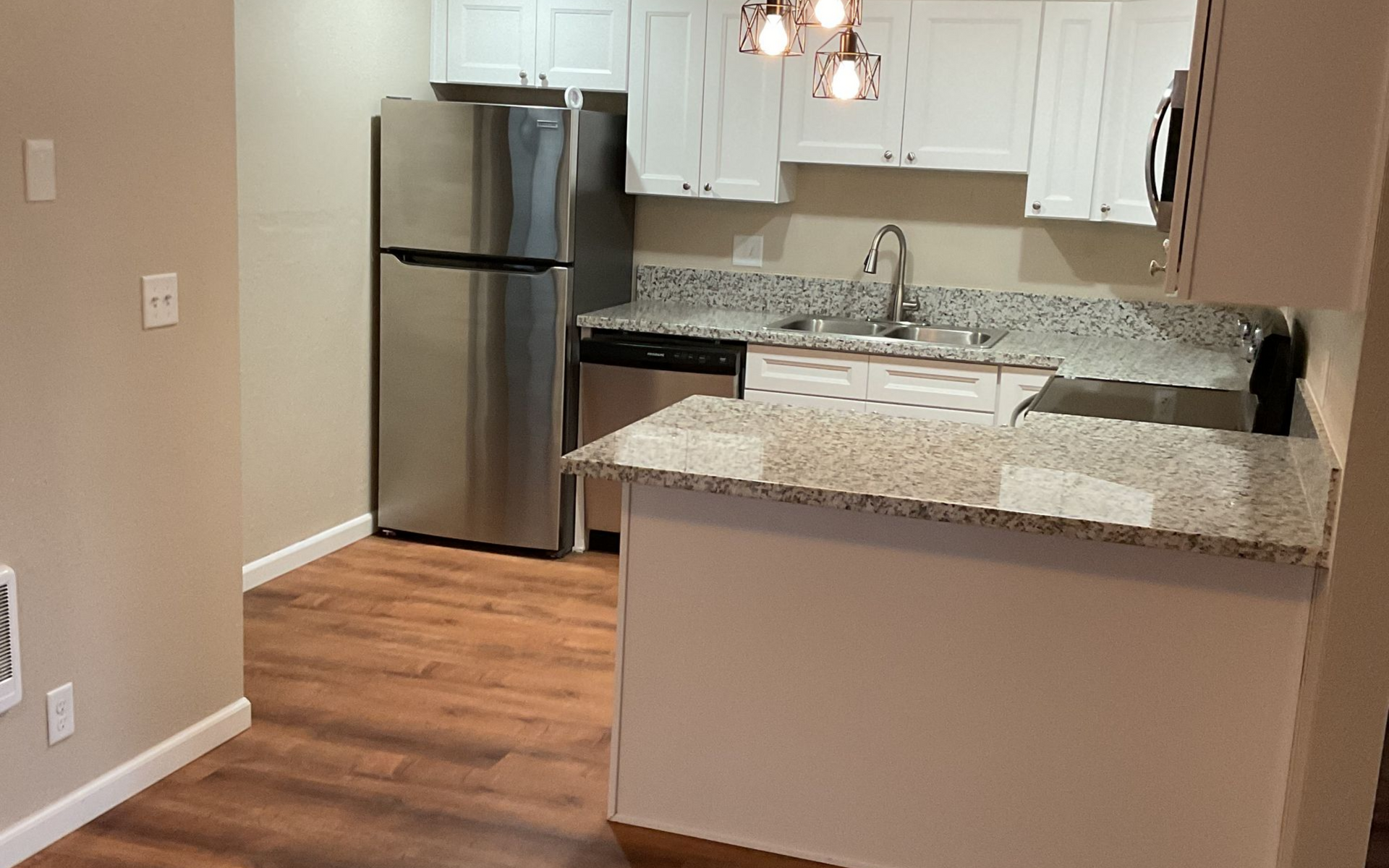 A kitchen with stainless steel appliances, white cabinets, and granite countertops.