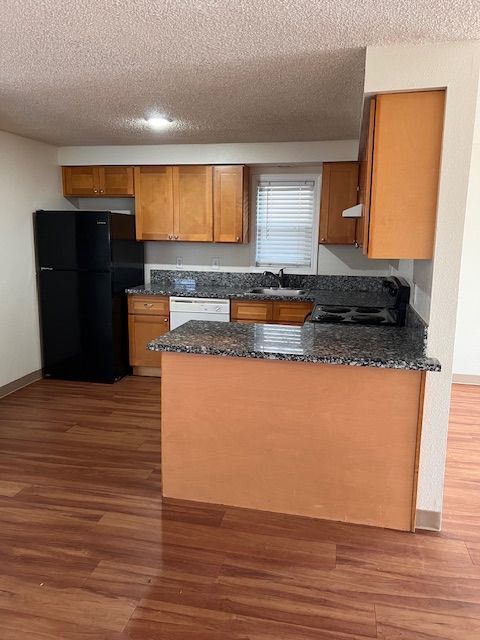 Kitchen with black appliances, wood cabinets, and granite countertops.