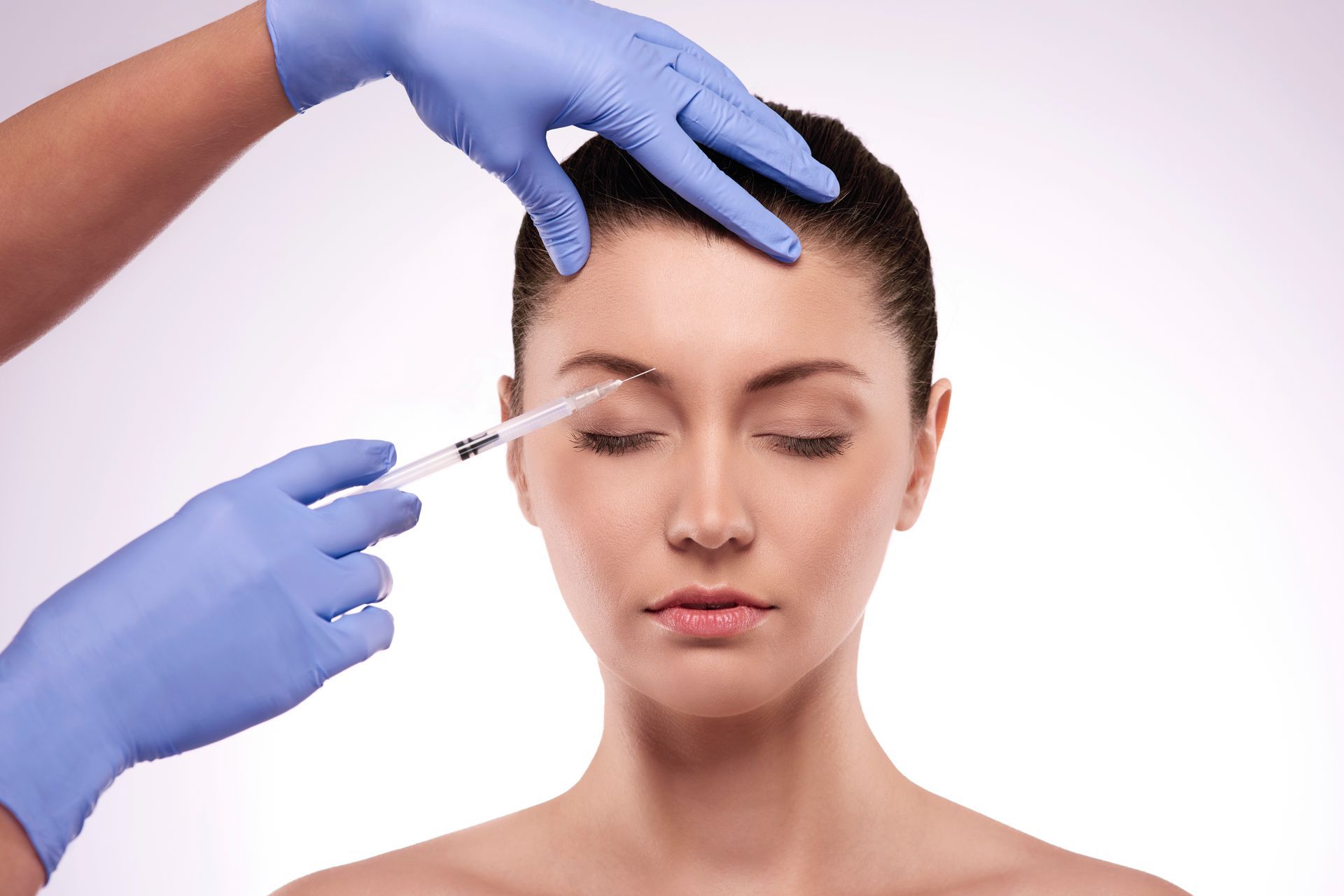 A woman is getting a botox injection in her forehead.