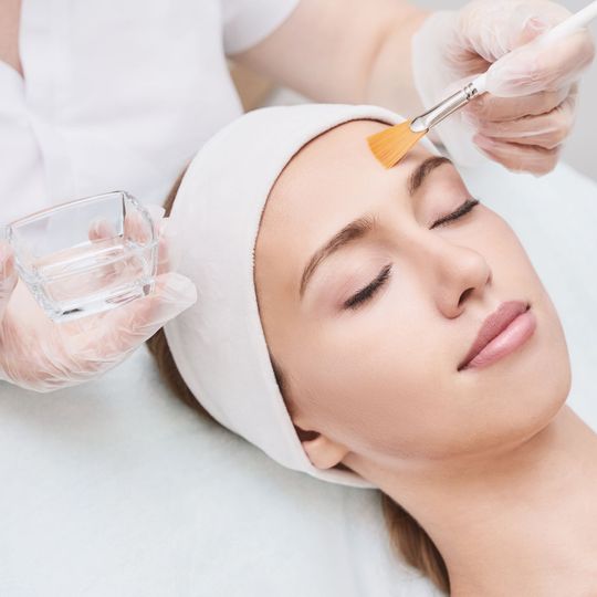 A woman is getting a facial treatment with a brush