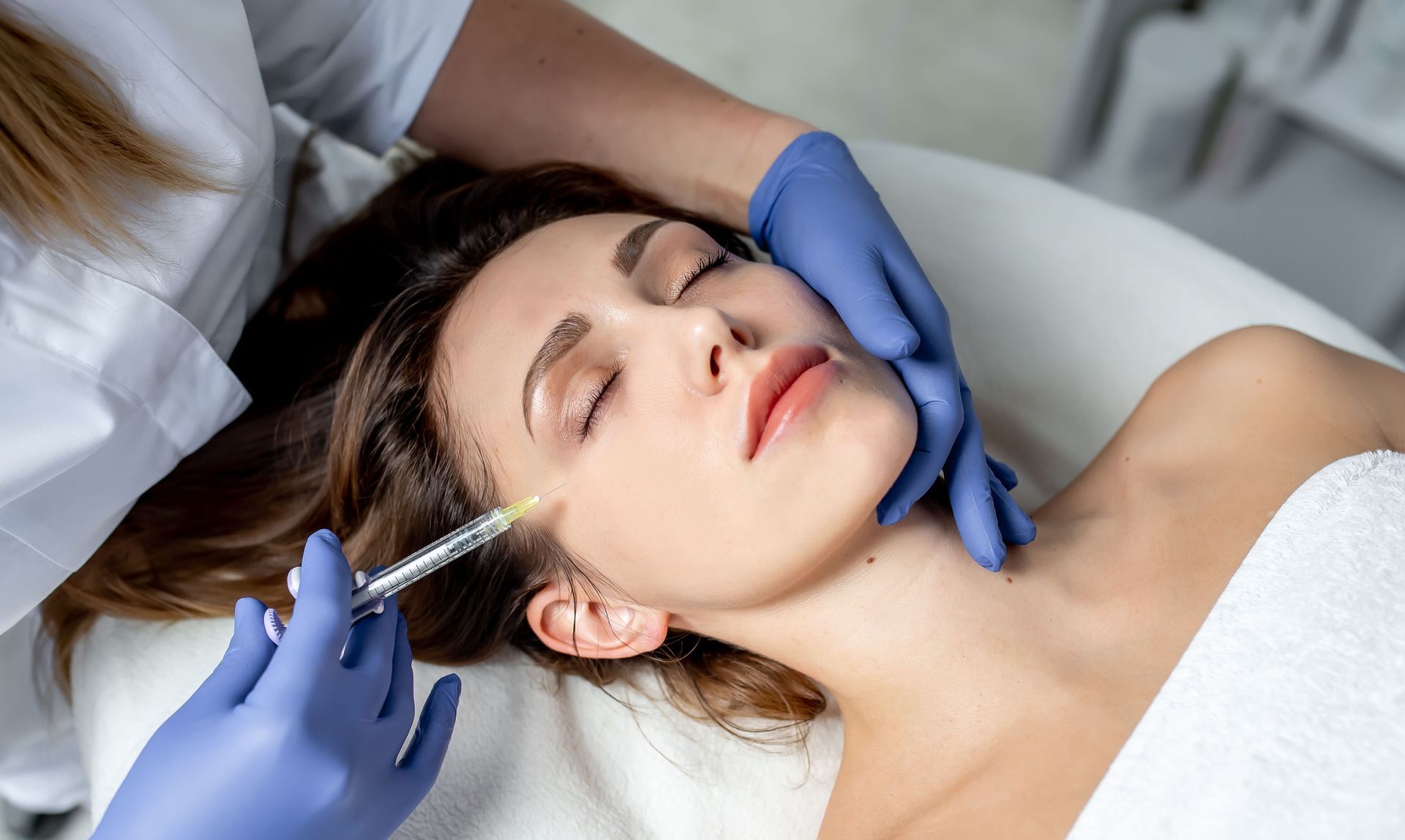 A woman is getting a botox injection in her face.