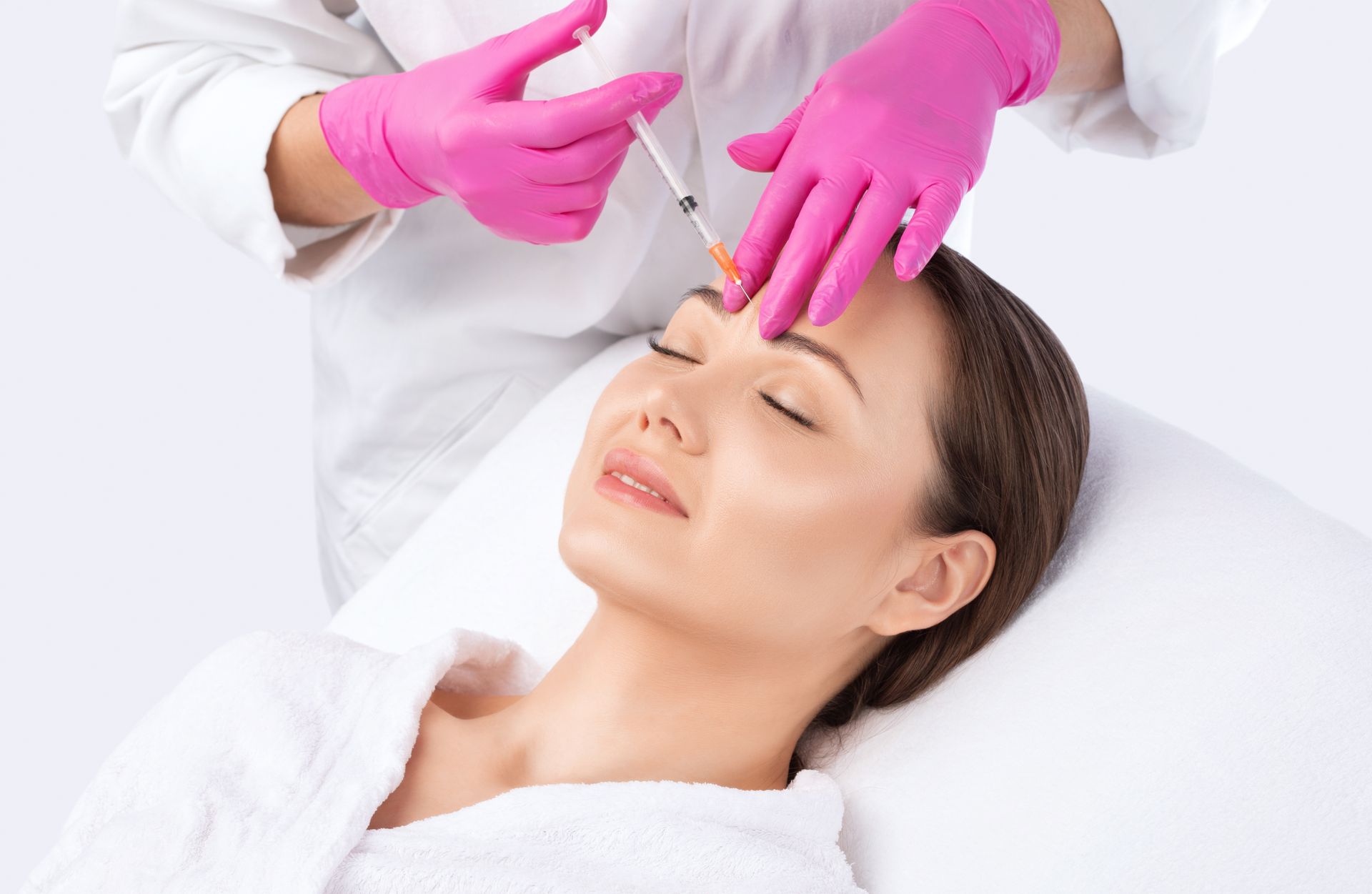 A woman is getting a botox injection in her forehead.