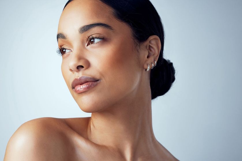 A close up of a woman 's face with a bun and earrings.