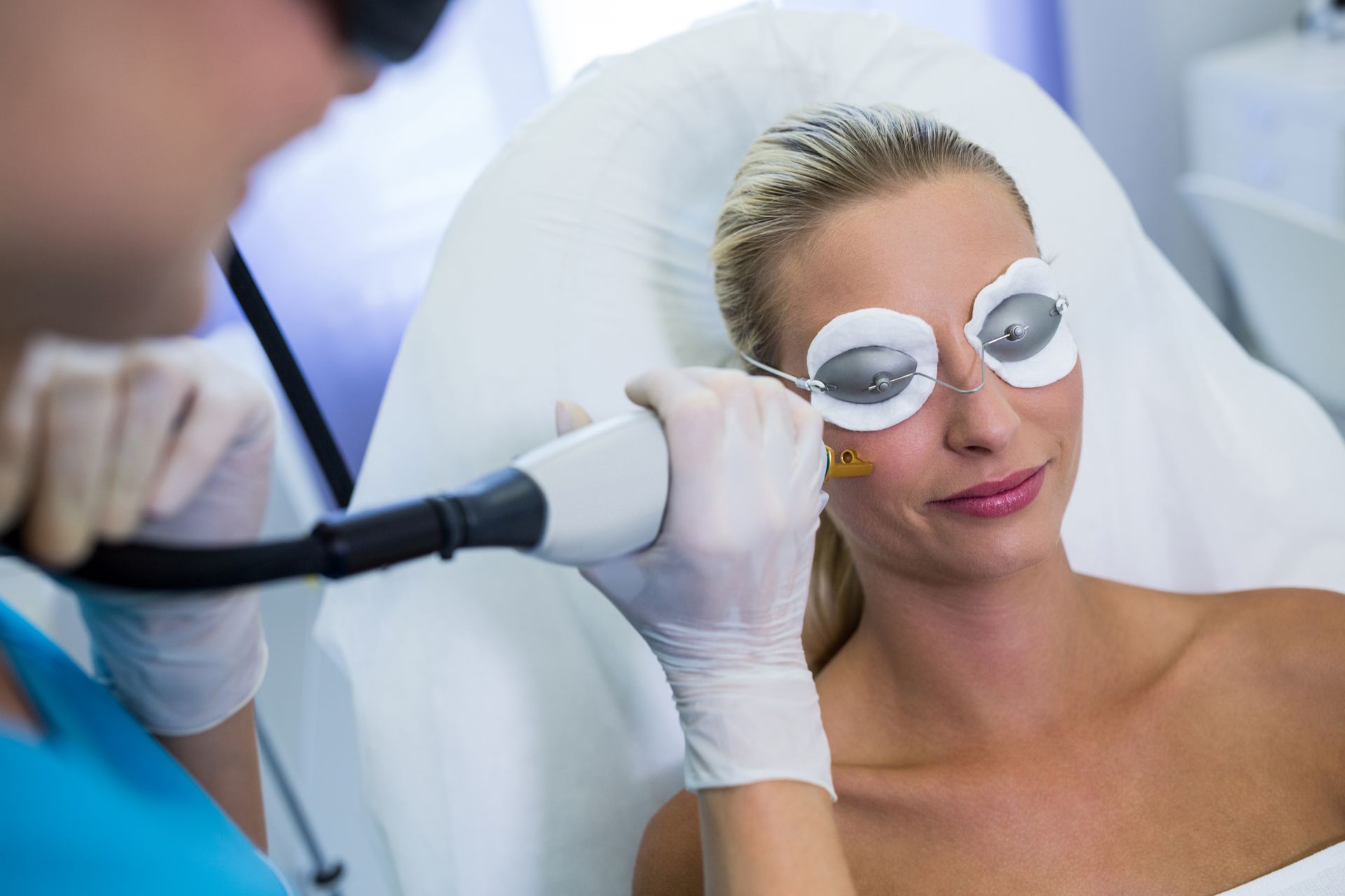 A woman is getting a laser treatment on her face.