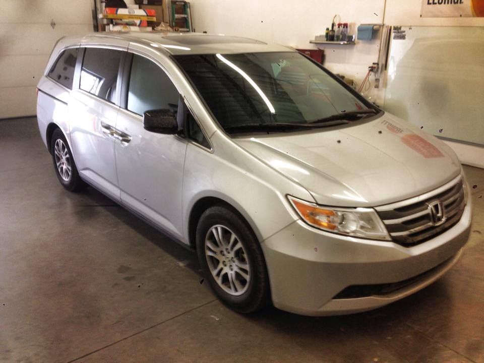 A silver honda minivan is parked in a garage