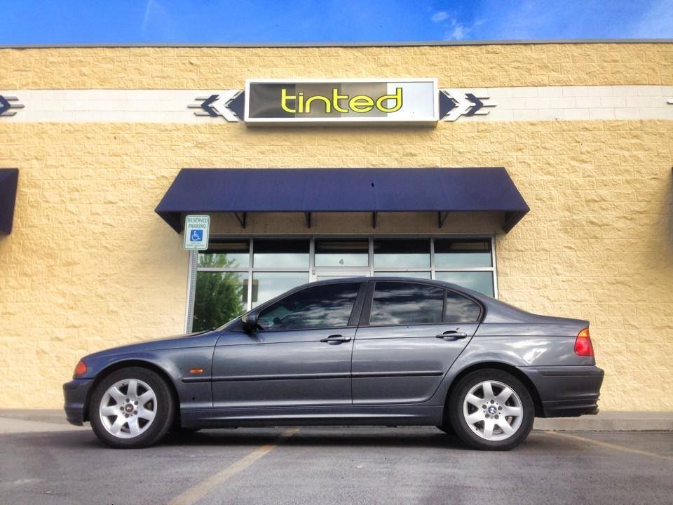 A car is parked in front of a tinted store