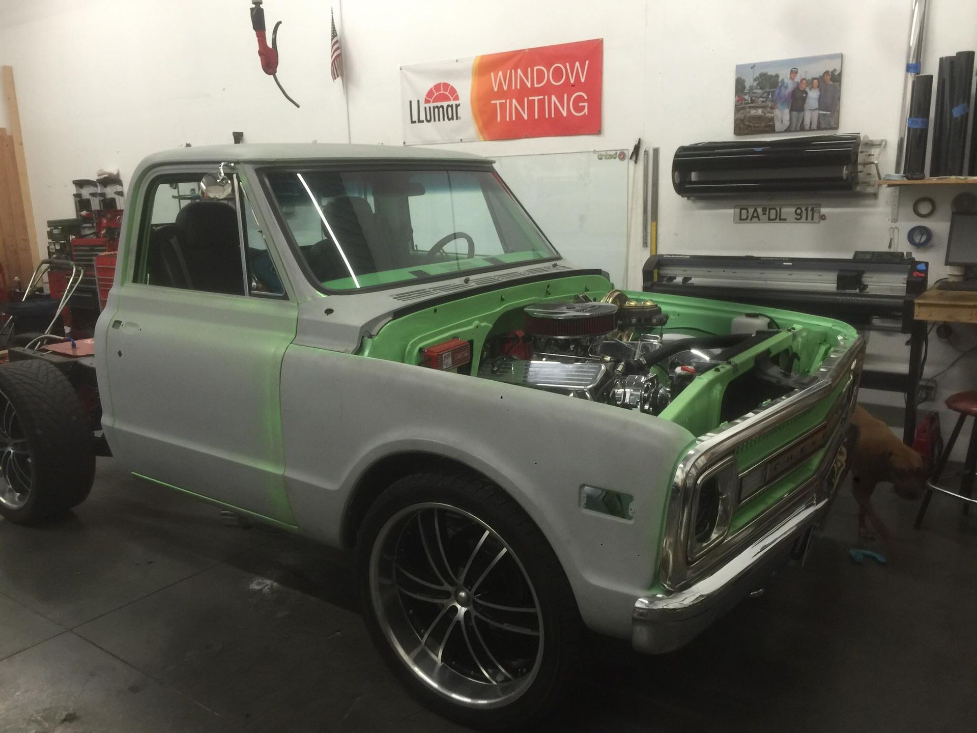 A green truck with the hood open is parked in a garage.