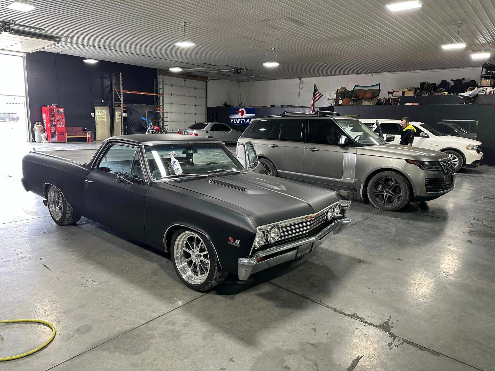 A couple of cars are parked in a garage.