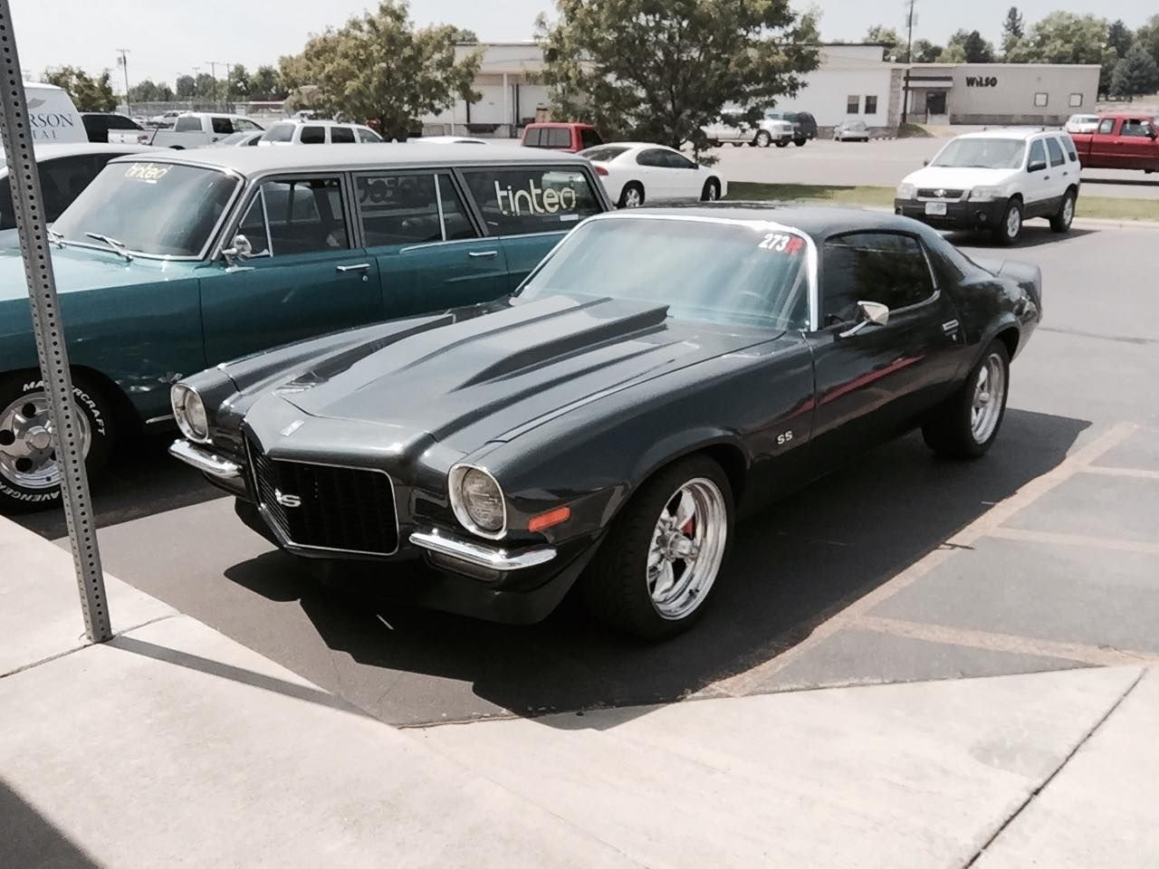 A black muscle car is parked in a parking lot
