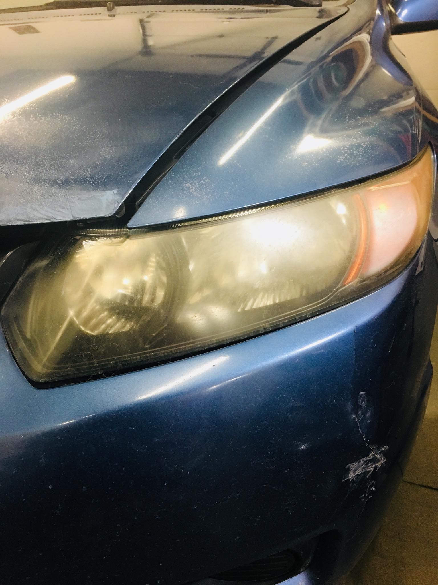 A close up of a blue car 's headlight in a garage.