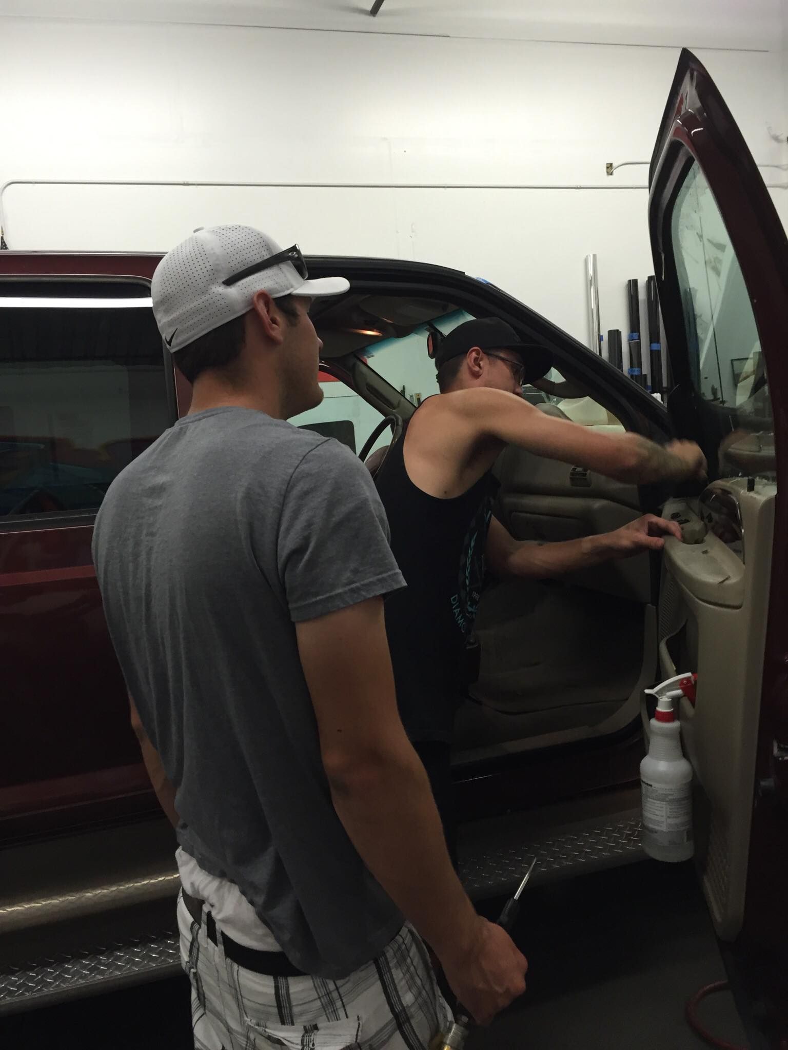 Two men are working on a car in a garage.