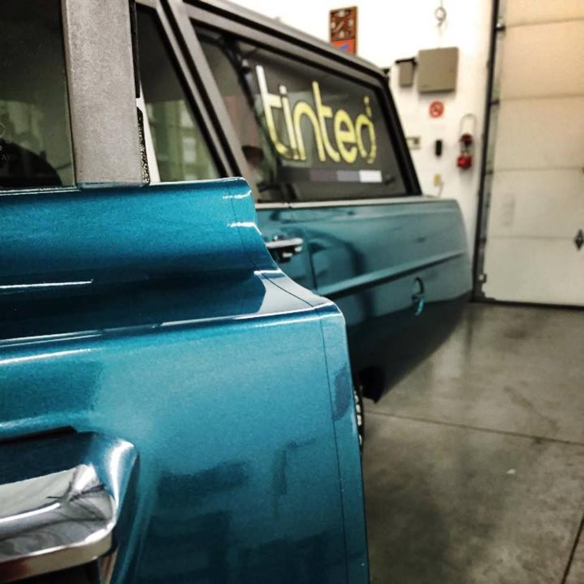 A blue tinted car is parked in a garage