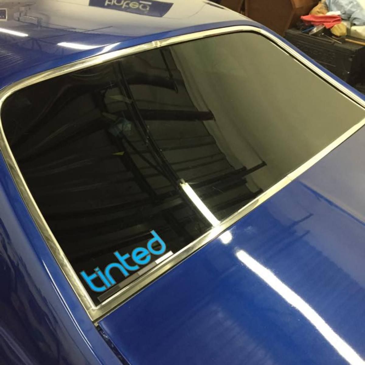 A blue car with a tinted sticker on the window