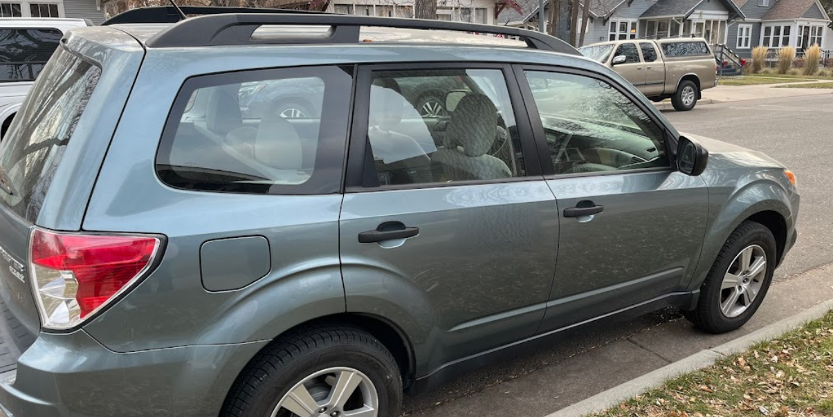 A blue suv is parked on the side of the road in a parking lot.