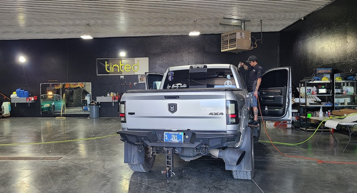 A silver truck is parked in a garage with its doors open.