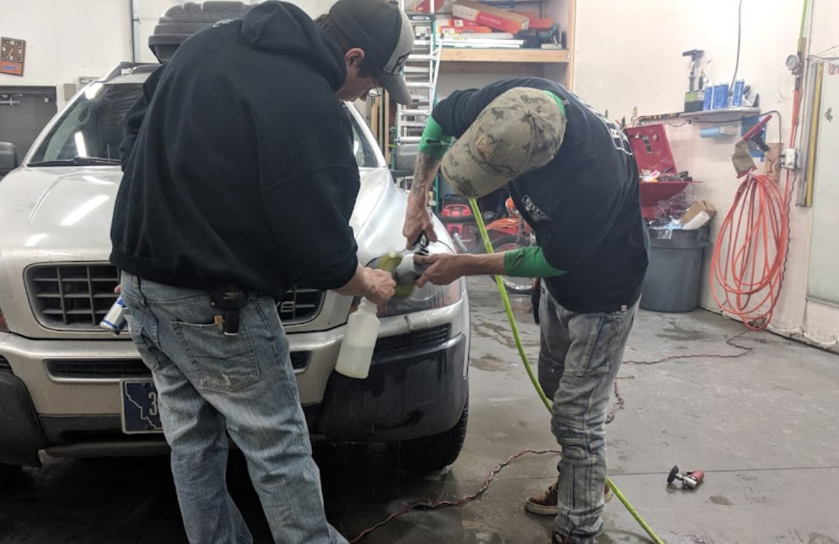 Two men are working on a car in a garage.