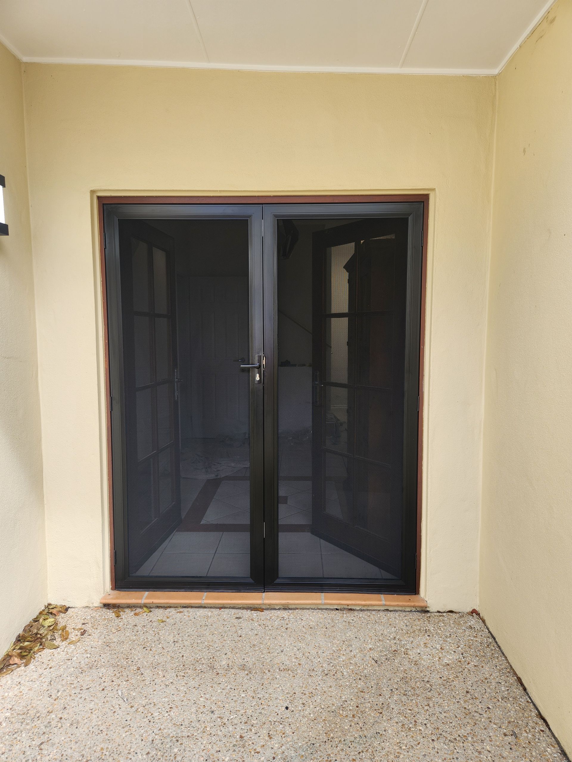 Black security screen doors, open. Beige walls and stone flooring  — Smart Screens Qld in Ormeau, QLD