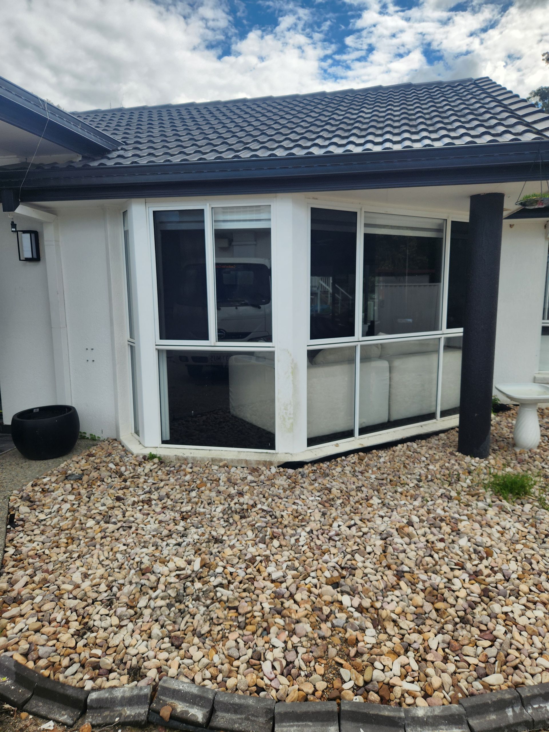 White house with gray roof, bay windows, and gravel landscaping — Smart Screens Qld in Ormeau, QLD