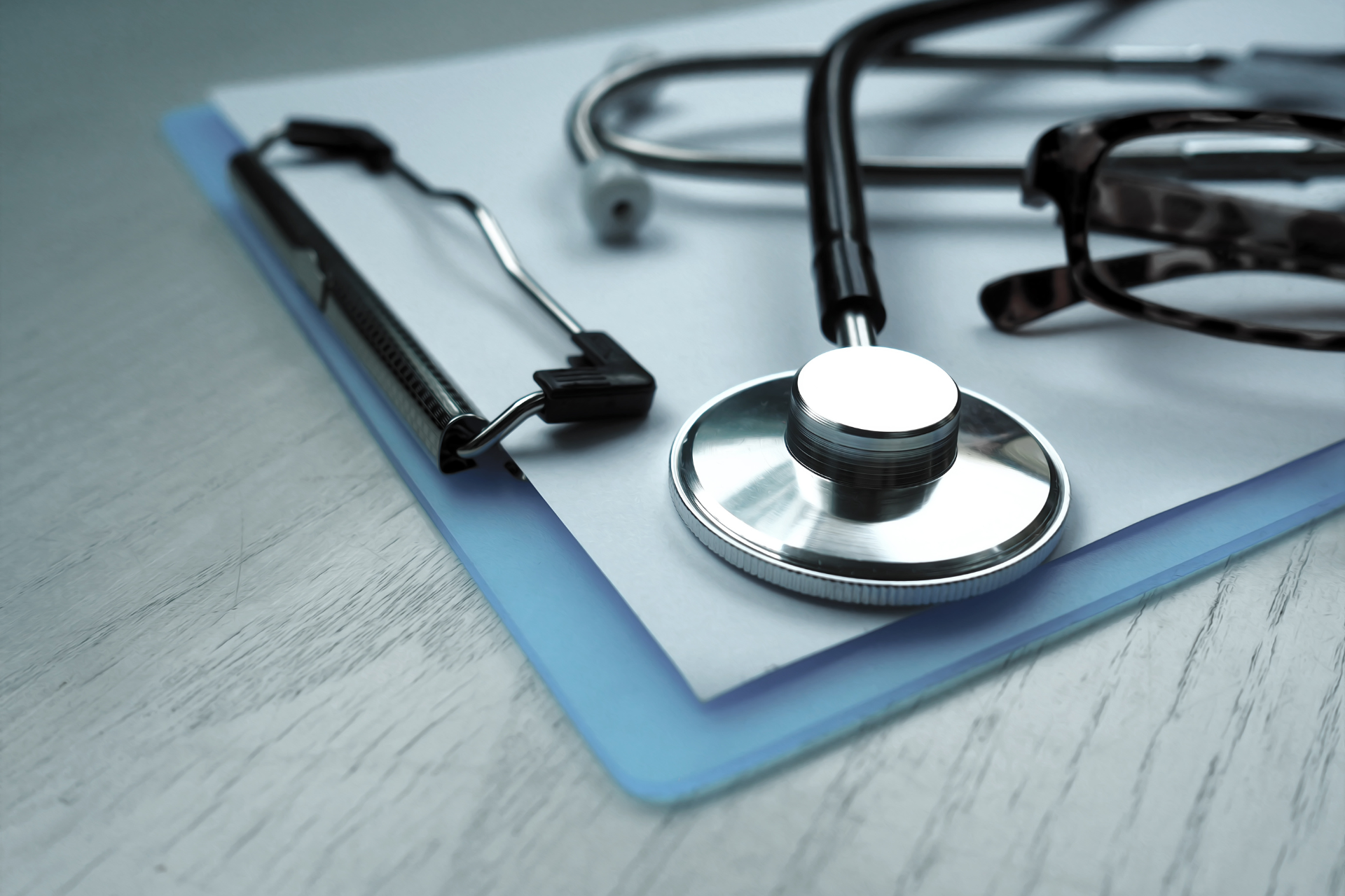 A clipboard with a stethoscope and glasses on it