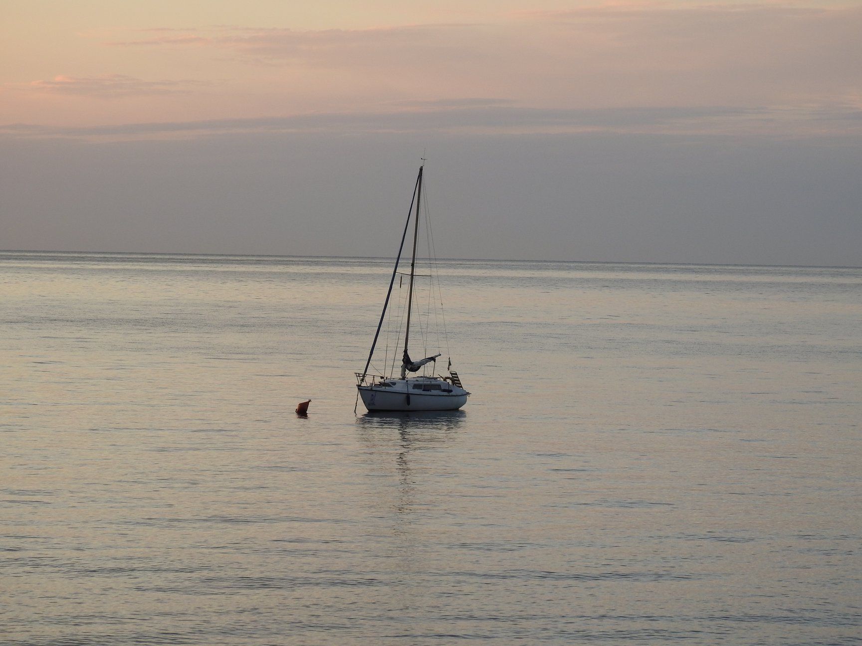 Una barca a vela è in mezzo all'oceano al tramonto