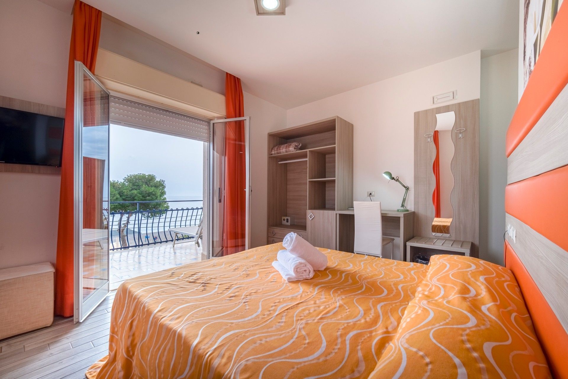 Una camera d'albergo con un letto grande e un balcone.