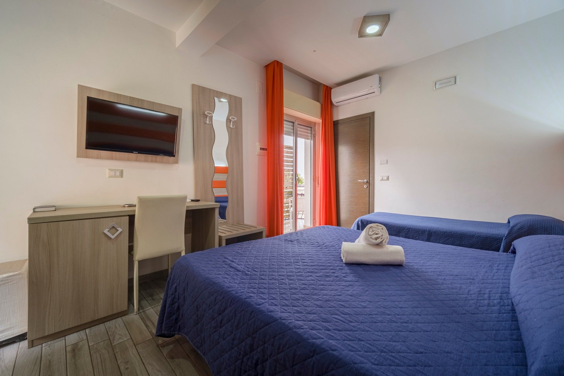 A hotel room with two beds, a desk and a television.