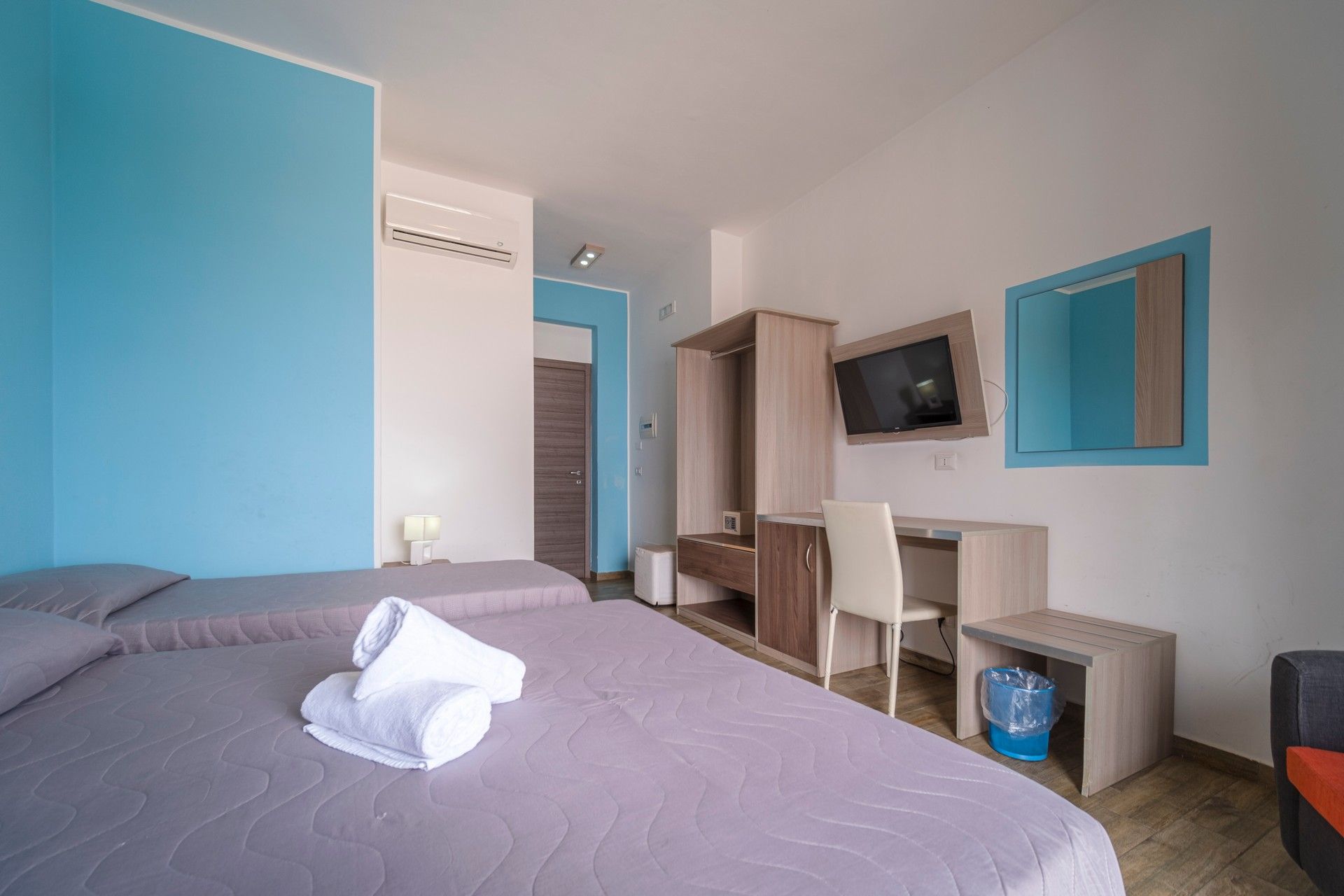 A hotel room with two beds, a desk and a television.