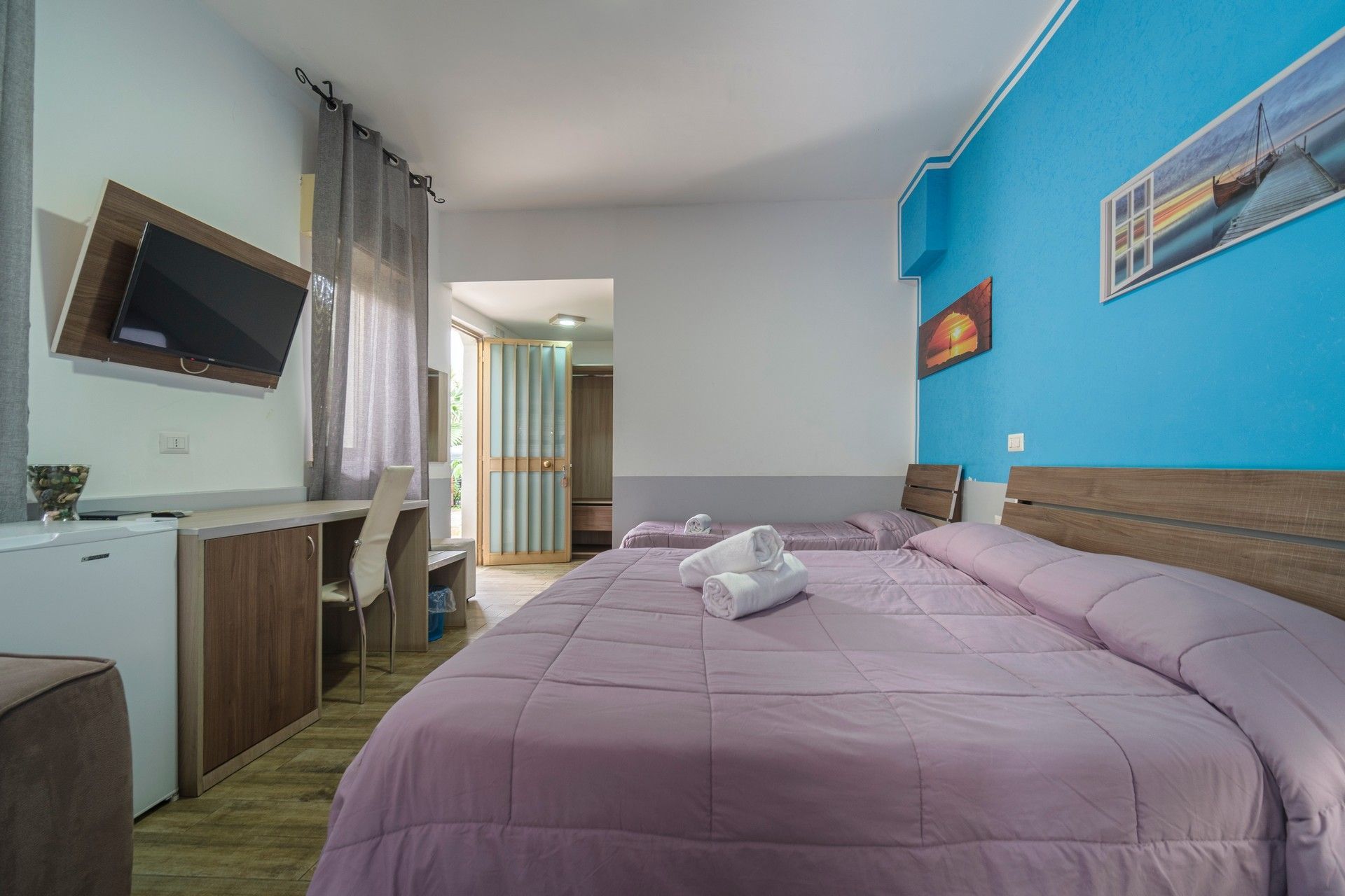 A hotel room with two beds, a desk and a television.