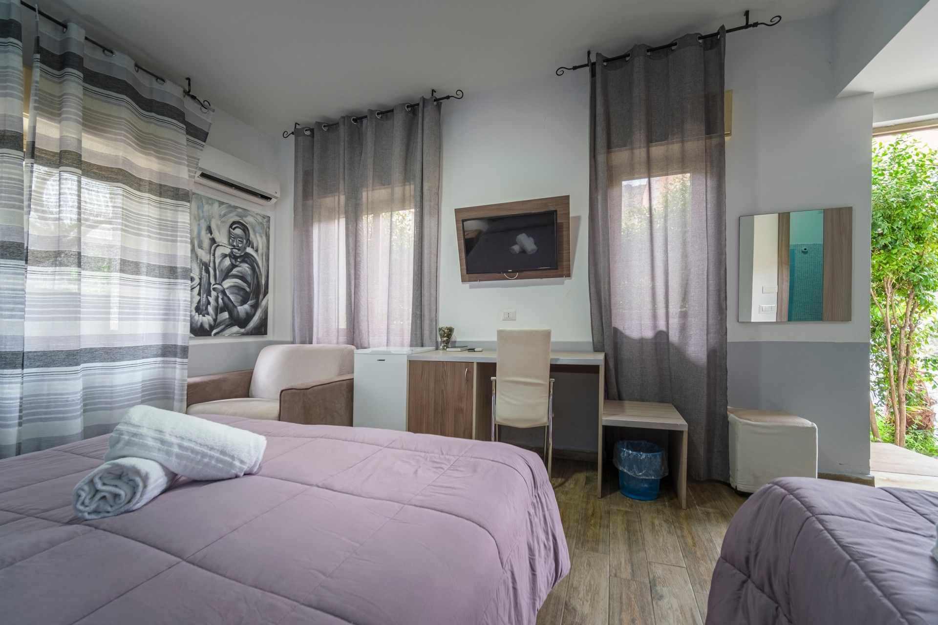 Una camera d'albergo con due letti, una sedia, una scrivania e uno specchio.