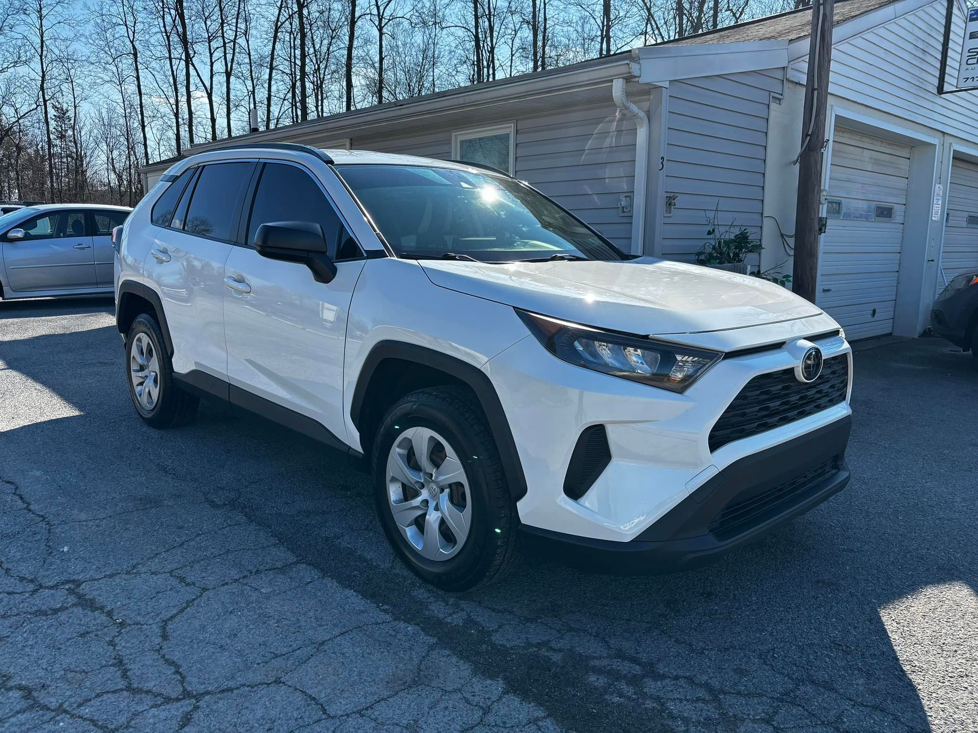 a white toyota rav4 is parked in front of a garage .