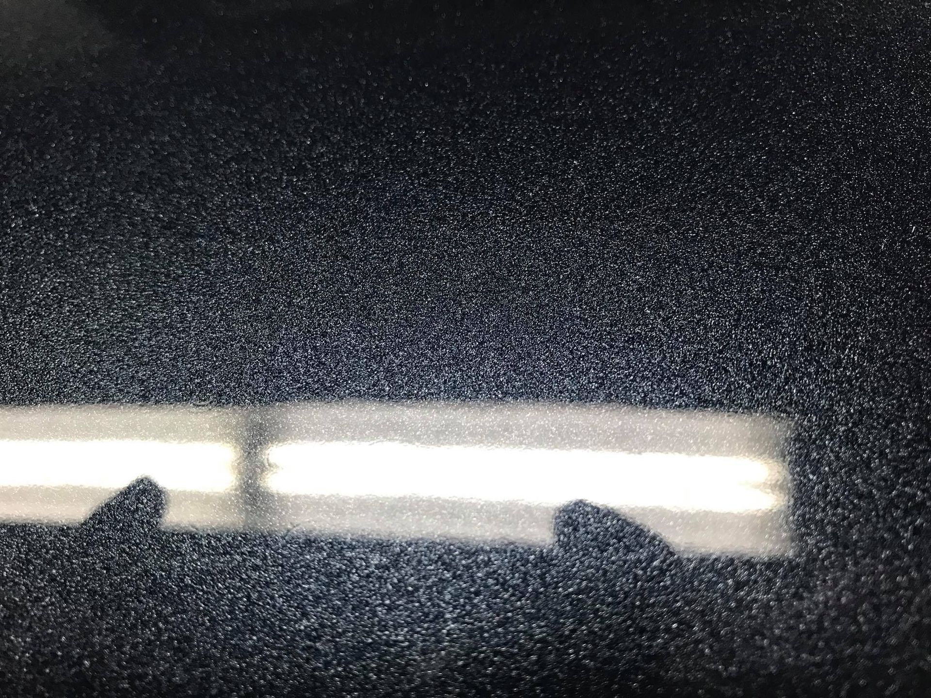 a close up of a black surface with a reflection of a window .