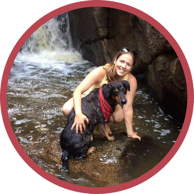 A woman kneeling next to a black dog in the water