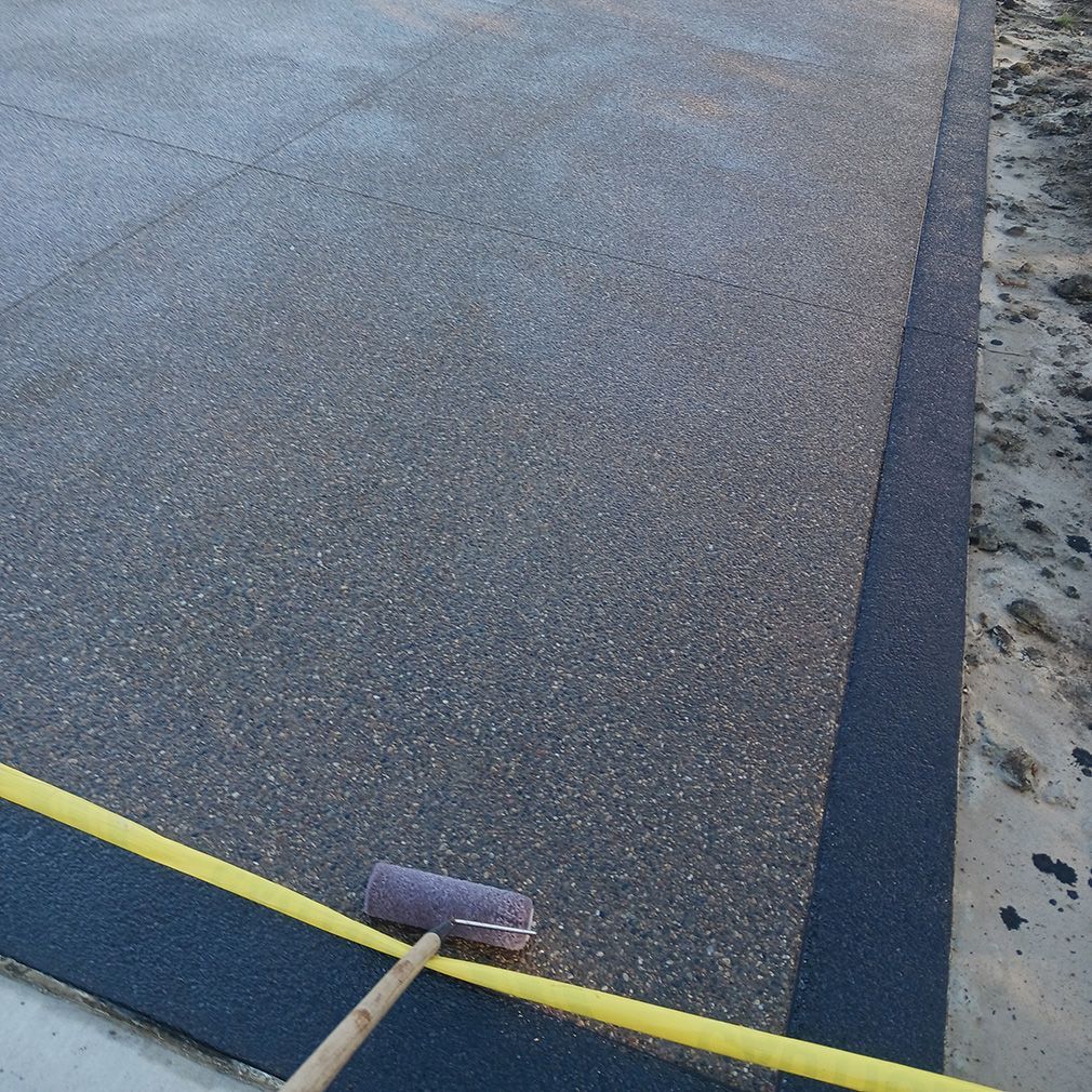 A roller is being used to paint a concrete surface